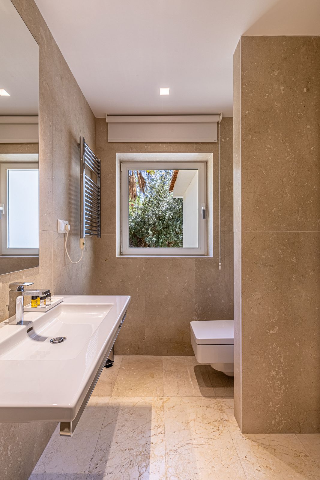 Bathroom with a wall-hung basin, a heated towel rail and a window