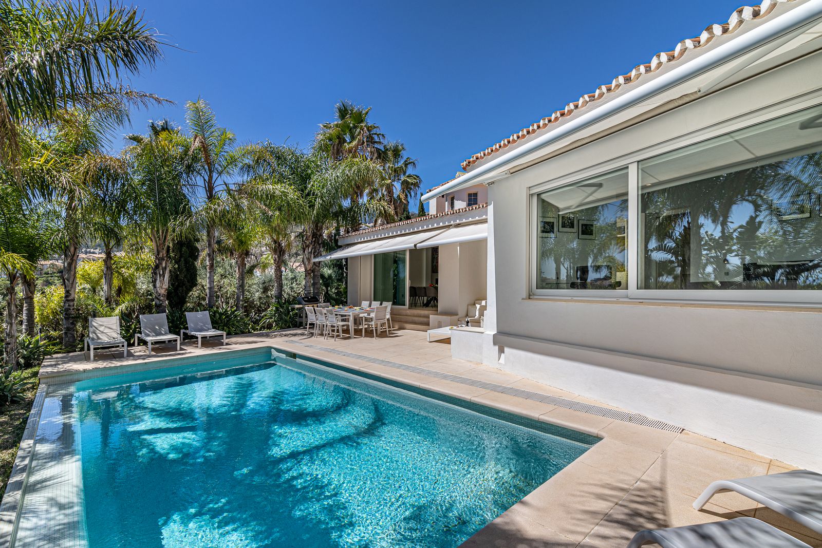 Private pool and palm trees in front of Villa Coníferas in Benalmádena, near Málaga