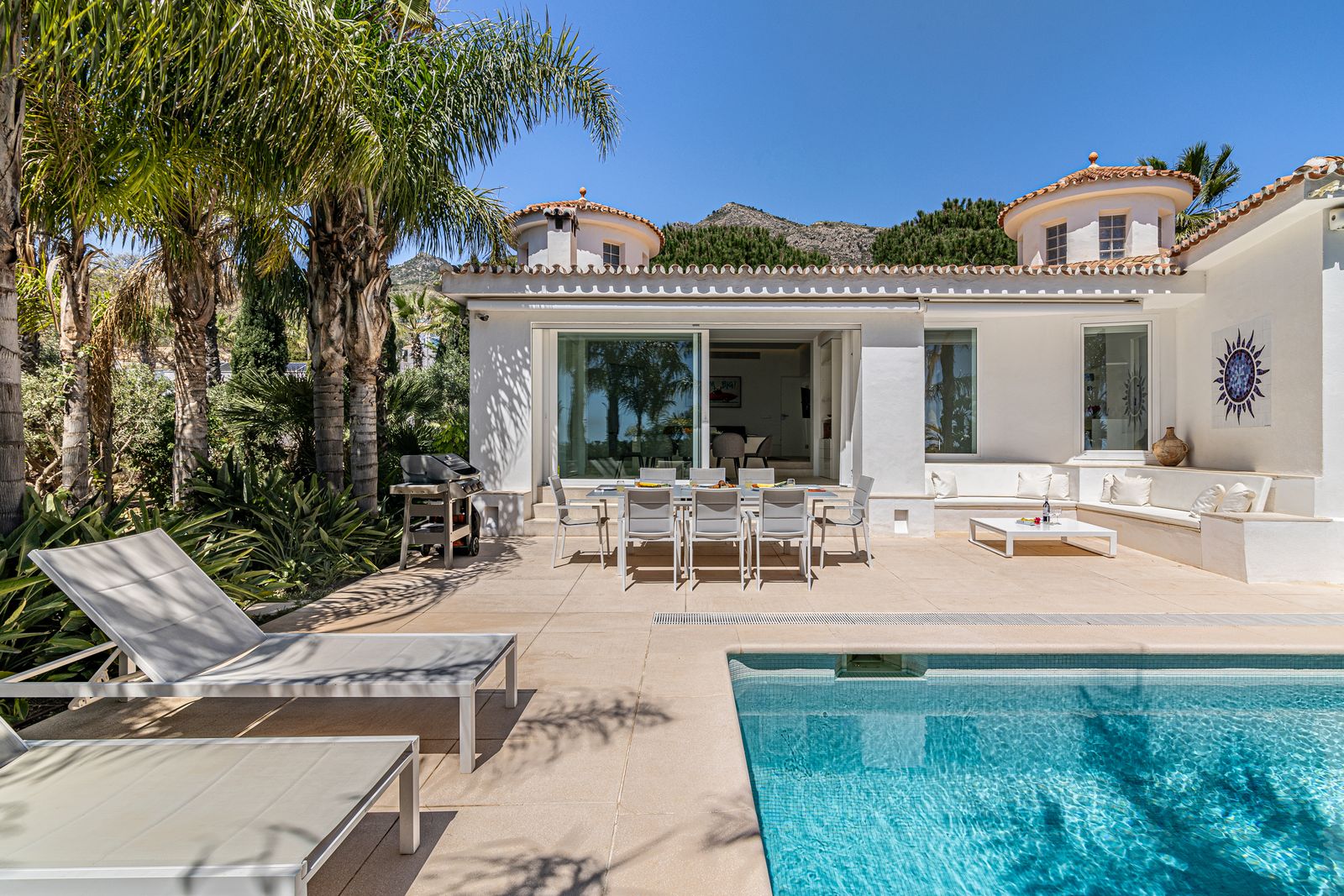Poolside terrace with a dining table and white outdoor seating