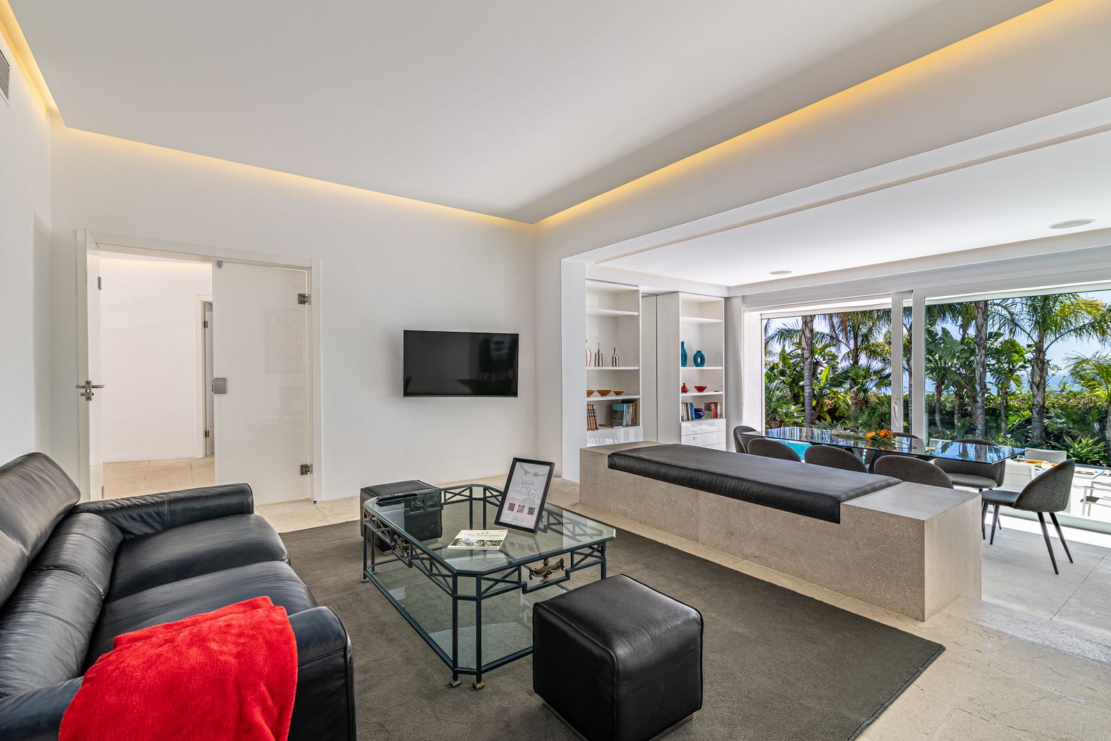Living room with black leather sofas, a red blanket and a glass coffee table